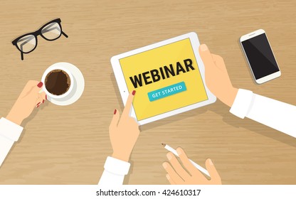 Human hands hold a tablet pc with webinar invitation on the display and showing it to his colleague. Top view of realistic wooden table on the office with grasses, smartphone and coffee cup