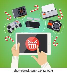 Human hands hold and tap on screen of smart tablet with buy button with shopping basket, goods are displayed around tablet. Buying online with mobile gadget as online shopping concept