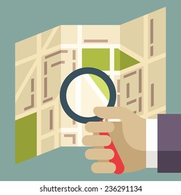 Human hands holding Magnifier and searching street on the map