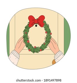 Human hands putting hanging ornate wreath on door during Christmas celebration