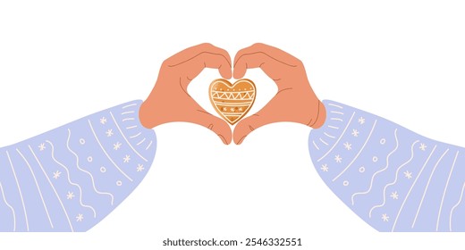 Human hands showing heart sign with Gingerbread Heart Cookie. Two hands wearing winter sweater. Homemade ginger pastries. Love symbol. Traditional Christmas baking. Tasty homemade cookie