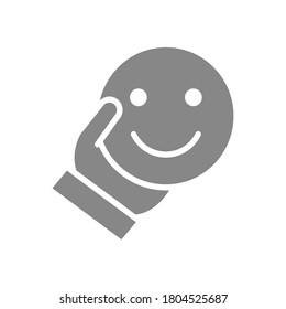 Human holding happy emoji gray icon. Share a good mood, emotions of satisfaction symbol