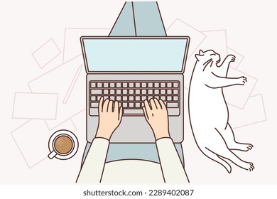 Der Mensch mit Laptop auf den Knien sitzt auf dem Boden und macht Online-Arbeit in der Nähe der schlafenden Katze und Tasse Kaffee. Hände von Bloggerinnen, die einen neuen Artikel in Laptop schreiben oder ein Buch schreiben, das sie im Internet verkaufen können