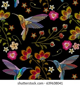 Humming bird and tropical flowers embroidery seamless pattern. Beautiful hummingbirds and exotic flowers embroidery on black background. Template for clothes, textiles, t-shirt design 