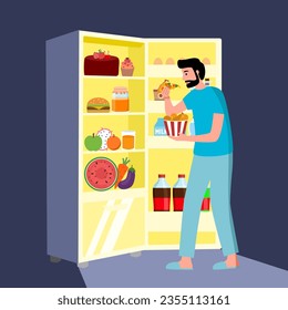 Hungry guy standing in front of opened fridge eating food at night. Man with night eating syndrome.