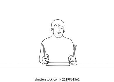 hungry man sitting at the table ready to eat and clutching a fork and knife - one line drawing vector. concept of insatiability, hunger, diet 