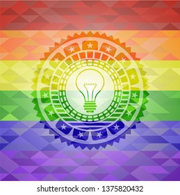 idea icon inside emblem on mosaic background with the colors of the LGBT flag