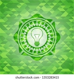 idea icon inside green emblem with triangle mosaic background
