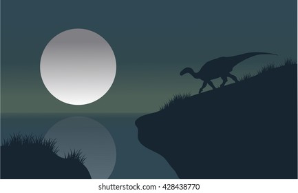 Iguanodon in riverbank with moon silhouette scenery a beautiful