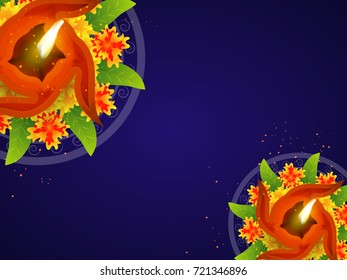 Illuminated oil lamp(diya) and flowers decorated blue background for Happy Diwali celebration.