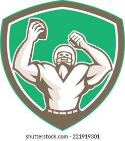 Illustration of an american football with helmet holding ball over head celebrating viewed from the front set inside shield crest on isolated background done in retro style. 