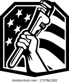 Illustration of an American plumber hand clutching adjustable pipe wrench or monkey wrench viewed from the side set inside shield crest with usa stars and stripes flag in the background done in retro 