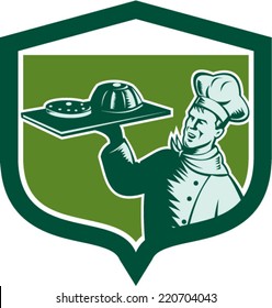 Illustration of a baker chef cook serving holding tray with food cake serving set inside shield crest on isolated background done in retro woodcut style. 