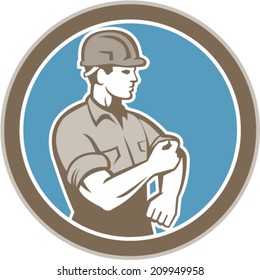 Illustration of a construction worker wearing hardhat rolling up sleeve facing side set inside circle on isolated background done in retro style.
