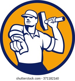 Illustration of a demolition worker wearing hat pointing holding hammer ready to strike set inside circle on isolated background done in retro style.