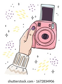 Illustration hand holds instant camera. The picture goes out of the camera. Black outline on white background.