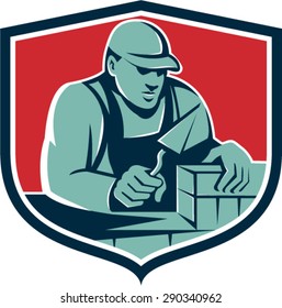 Illustration of a mason masonry construction worker holding trowel working on bricks viewed from front set inside shield crest done in retro style. 