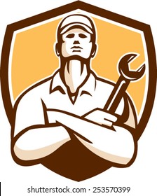 Illustration of a mechanic worker wearing hat arms crossed holding wrench looking up set inside shield crest on isolated background done in retro style.