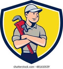 Illustration of a plumber wearing hat looking to the side arms crossed holding monkey wrench viewed from front set inside shield crest on isolated background done in cartoon style.