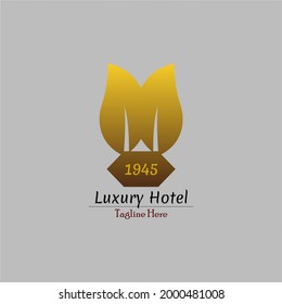 imagen de un logo de un hotel de lujo con un concepto de edificio verde, representado con dos hojas de oro, que ha existido durante mucho tiempo. Este logotipo también es adecuado para los restaurantes de lujo y saludables