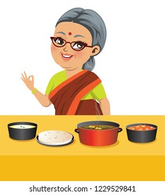 An Indian fat old grandmother wearing a saree has just cooked wholesome Indian food with spicy curried veggies, roti (Indian flat bread) and halwa or sweet carrot pudding.