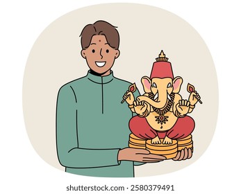 Indian man holds figurine of Lord Ganesha and smiles, demonstrating national amulet that brings good luck and success. Lord Ganesha made of ceramics in hands guy inviting to festival of hindi culture