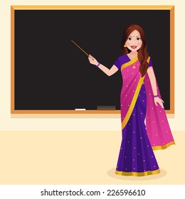 Indian teacher wearing a saree holding a stick in front of blackboard