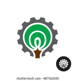 Industrial logo with stylized tree silhouette and gear around