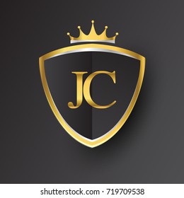 Initial logo letter JC with shield and crown Icon golden color isolated on black background.