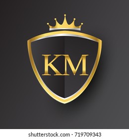 Initial logo letter KM with shield and crown Icon golden color isolated on black background.