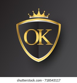 Initial logo letter OK with shield and crown Icon golden color isolated on black background, logotype design for company identity.