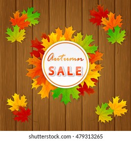 Inscription Autumn sale with round card and colored maple leaves on wooden background, illustration.