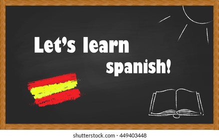 The inscription "Let's learn Spanish!" on blackboard with a wooden frame. Drawing sun, books and the Spanish flag on a school blackboard with wooden frame.