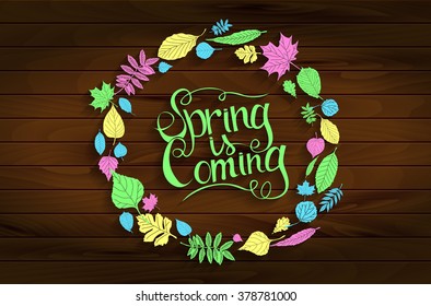 Inscription Spring is coming on wooden background in a frame of colored leaves. Hand draw, vector illustration. Graphic design.