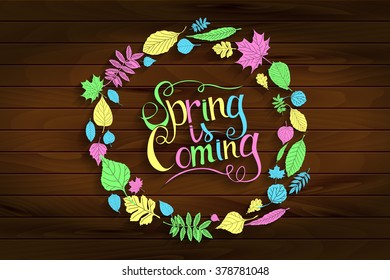 Inscription Spring is coming on wooden background in a frame of colored leaves. Hand draw, vector illustration. Graphic design.