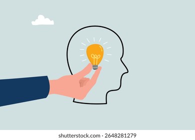 Conceito de inspiração. Mão segurando lâmpada luminosa, colocando no cérebro humano.