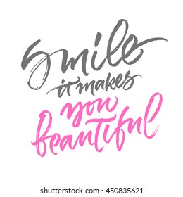 Inspirational phrase 'Smile, it makes you beautiful'. Romantic and warm greeting card design. Handwritten brush calligraphy.