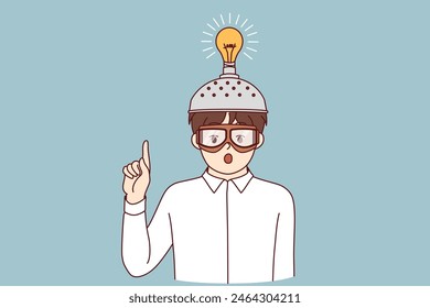 Inspired boy invented new idea and shows finger up standing with funny helmet with light bulb. Child inhabitant invented device to improve brain function and intellectual capabilities