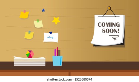 Interior of a room with a wooden desk having cute stationary like a bright and colorful paperweight along with a coming soon announcement banner hanging on the wall with post it notes next to it