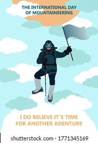 International Day of mountaineering. An experienced climber stands on peak of a mountain waving a flag while clouds surround it.