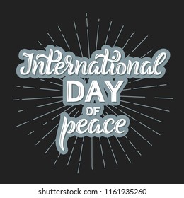 Internationnal Peace Day text with blue outline. Isolated on dark background with rays. Holiday card with lettering.