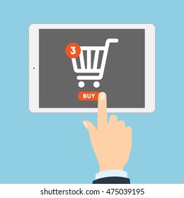 Internet Shopping Concept. Hand Pulling Buy Button On Tablet. Three Items In Shopping Cart. E-commerce Concept. Shopping Online.