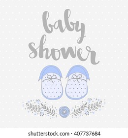 Invitation card to a Baby Shower with baby blue booties and floral design elements. Background polka dot pattern. Calligraphy lettering