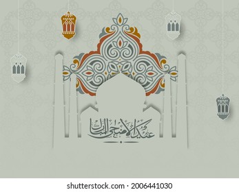 Islamic festival of sacrifice concept with Arabic calligraphic text Eid-Ul-Adha Mubarak with exquisite floral pattern, mosque and paper lanterns. 
