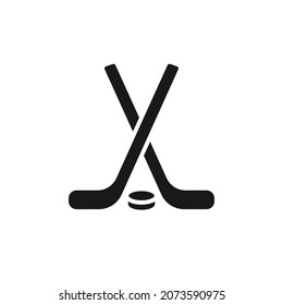 Icono negro aislado de bastón de hockey y puck sobre fondo blanco. Silueta del ícono del hockey sobre hielo. Diseño plano con logotipo. Equipamiento deportivo de invierno.