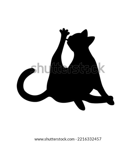 Isolated black silhouette of cat on white background. Flat cartoon cat licks paw.