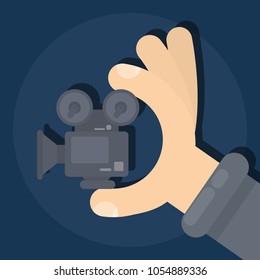 Isolated tiny film camera in hands on dark background.