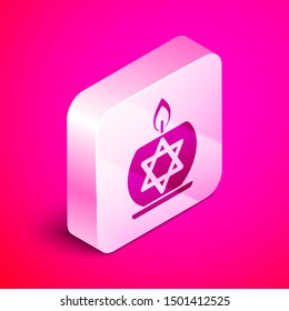 Isometric Burning candle in candlestick with star of david icon isolated on pink background. Cylindrical candle stick with burning flame. Silver square button. Vector Illustration