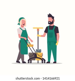 Janitor couple, Man and woman in uniform working together with professional equipment.  Cleaning service concept. Cleaners pushing trolley cart with equipment, full length flat.