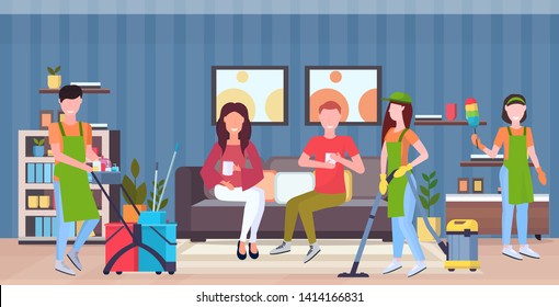 janitors team cleaners in uniform working together with professional equipment cleaning service concept couple sitting on couch modern living room interior flat full length horizontal